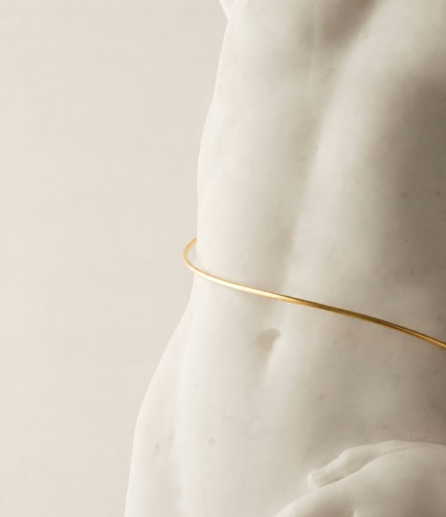 Torso di statua in marmo cinto da un filo dorato